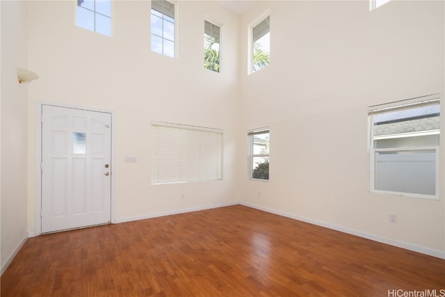 entrance foyer with plenty of natural light, wood-type flooring, and a high ceiling