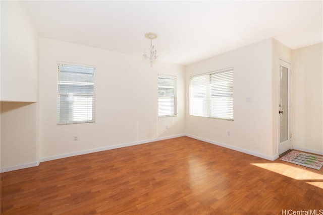 unfurnished room featuring hardwood / wood-style floors and a notable chandelier