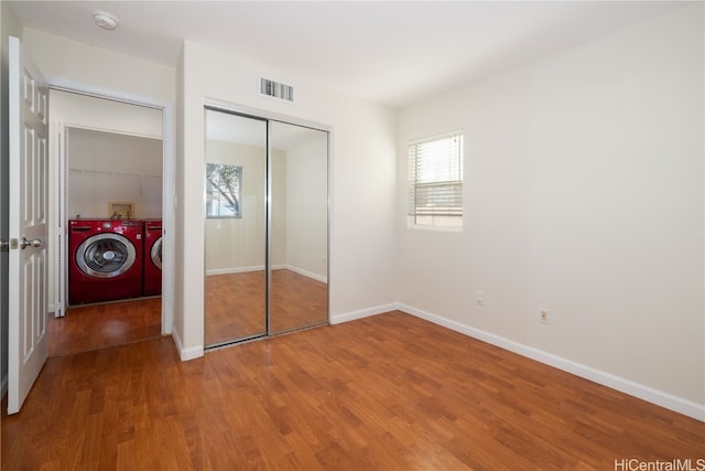 unfurnished bedroom featuring washer and dryer, wood-type flooring, and a closet