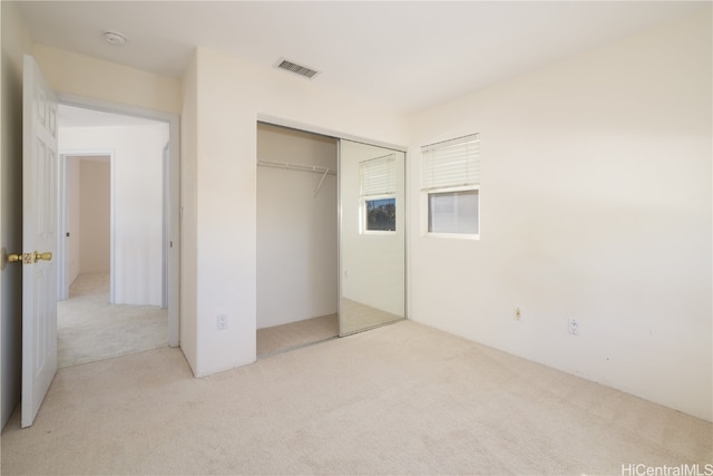 unfurnished bedroom featuring light colored carpet and a closet