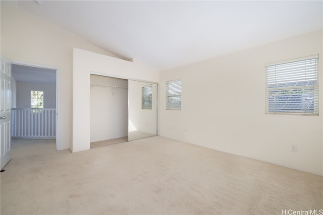 unfurnished bedroom featuring multiple windows, light carpet, and vaulted ceiling