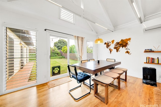 dining room with beam ceiling, high vaulted ceiling, a wall mounted air conditioner, and light wood-type flooring