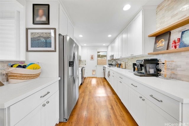 kitchen with appliances with stainless steel finishes, tasteful backsplash, sink, light hardwood / wood-style flooring, and white cabinets