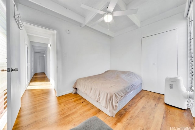 bedroom with ceiling fan, a closet, beamed ceiling, and light wood-type flooring