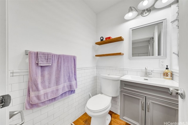 bathroom featuring vanity, toilet, wood-type flooring, and tile walls