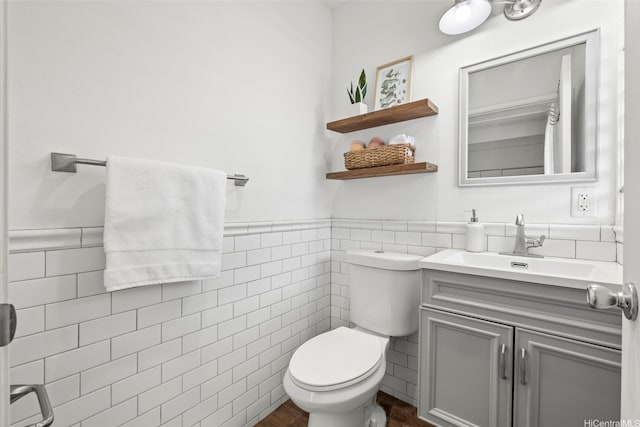 bathroom with vanity, toilet, wainscoting, tile walls, and wood finished floors