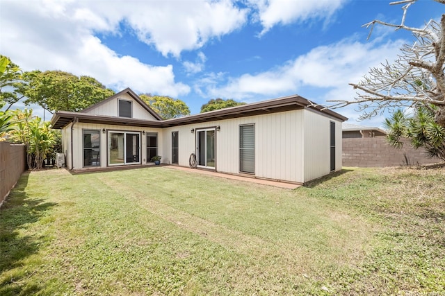 back of property with a fenced backyard and a lawn