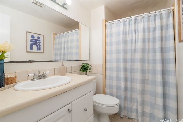 bathroom featuring tile patterned flooring, vanity, toilet, and walk in shower