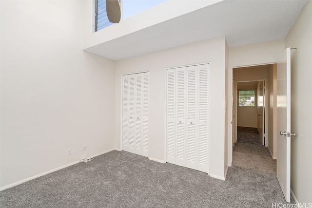 unfurnished bedroom with multiple closets and carpet floors