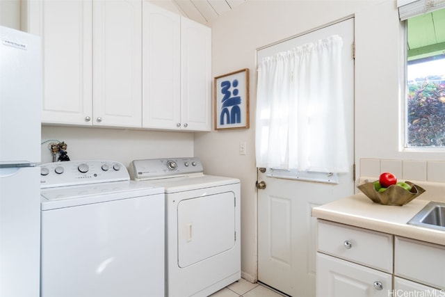 clothes washing area with cabinets, sink, washer and dryer, and light tile patterned flooring