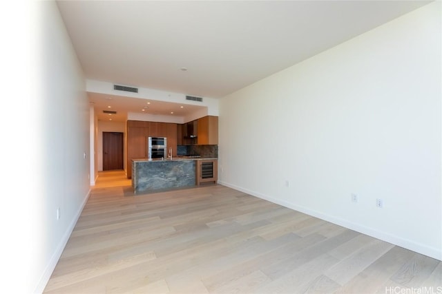 unfurnished living room with wine cooler and light hardwood / wood-style flooring