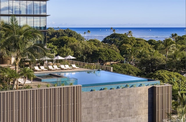 view of swimming pool featuring a water view and a hot tub