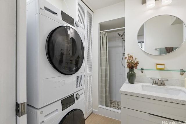 laundry room with stacked washer / drying machine, sink, and light hardwood / wood-style flooring