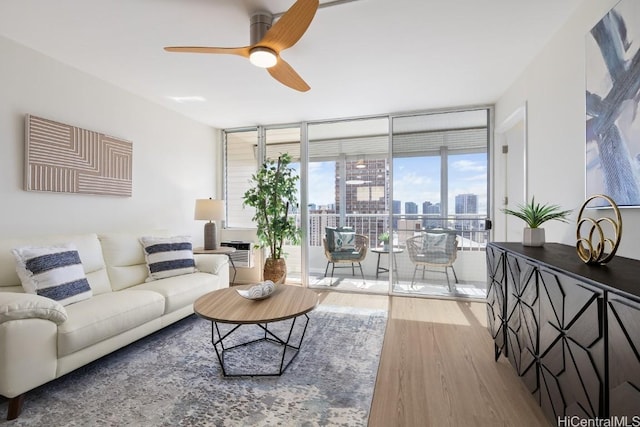 living room featuring ceiling fan, light hardwood / wood-style floors, and a wall of windows