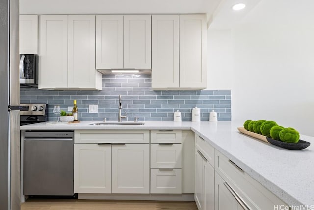 kitchen featuring white cabinets, appliances with stainless steel finishes, backsplash, and sink