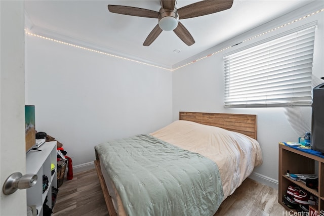 bedroom featuring ceiling fan, wood-type flooring, and ornamental molding