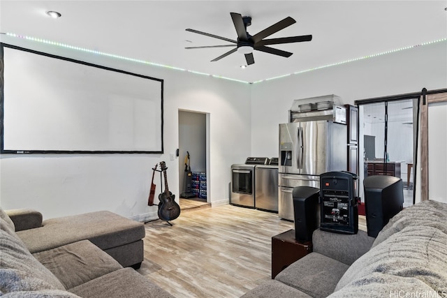 home theater featuring ceiling fan, light wood-type flooring, and independent washer and dryer