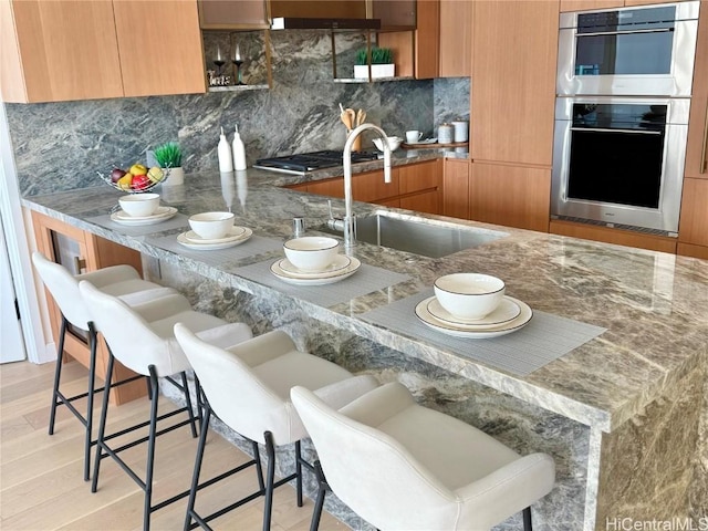 kitchen featuring tasteful backsplash, appliances with stainless steel finishes, a kitchen bar, and sink