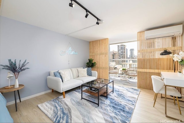 living room with hardwood / wood-style floors, rail lighting, and a wall unit AC