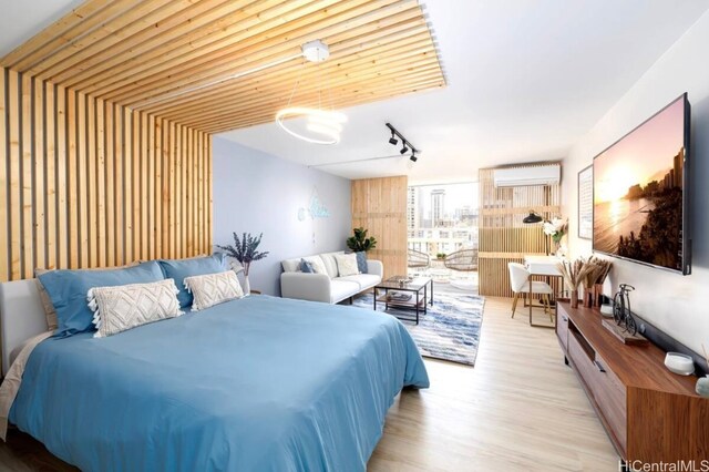 bedroom featuring light wood-type flooring, rail lighting, and a wall mounted AC