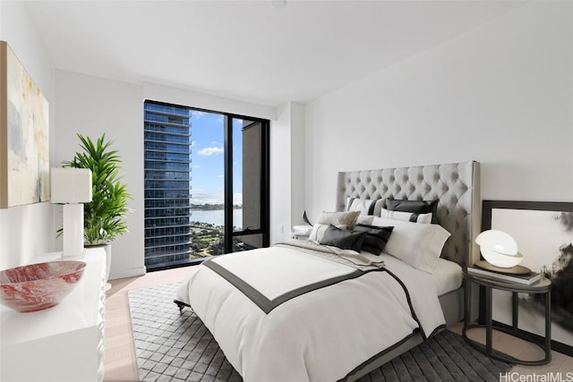 bedroom with a water view, wood finished floors, and access to exterior