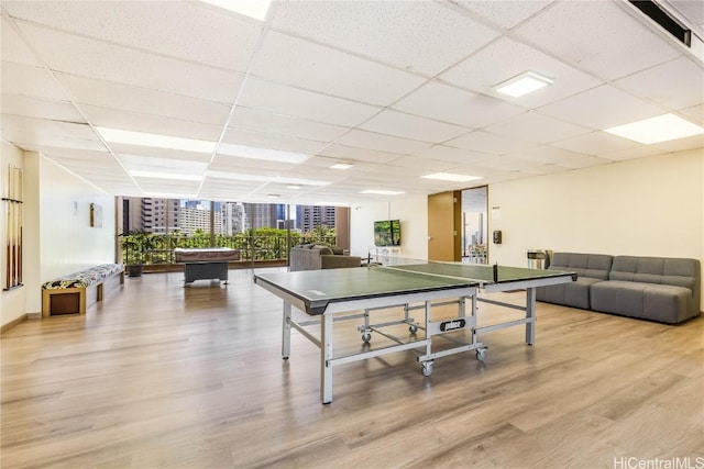 playroom featuring a paneled ceiling, expansive windows, and light hardwood / wood-style floors