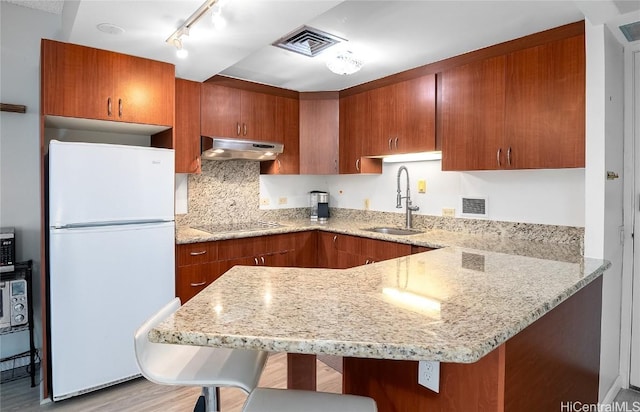 kitchen featuring a kitchen breakfast bar, sink, light wood-type flooring, white fridge, and extractor fan