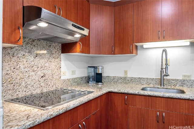 kitchen with decorative backsplash, light stone countertops, black electric cooktop, and sink