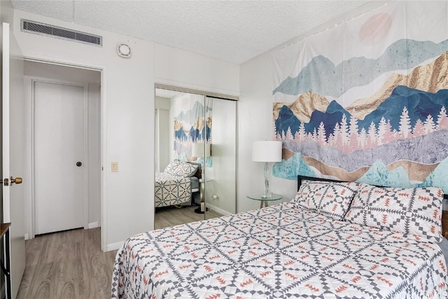 bedroom with wood-type flooring, a textured ceiling, and a closet