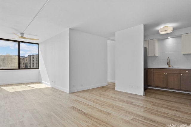 unfurnished living room with light hardwood / wood-style floors, ceiling fan, and sink