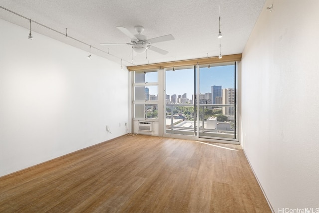 spare room with a textured ceiling, hardwood / wood-style flooring, a wealth of natural light, and ceiling fan