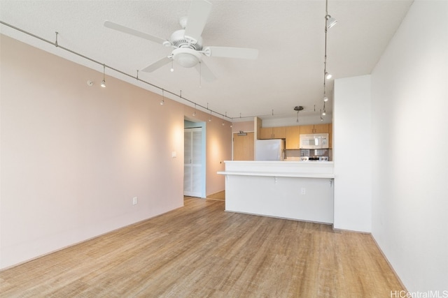 unfurnished living room featuring ceiling fan, light wood-type flooring, and a textured ceiling