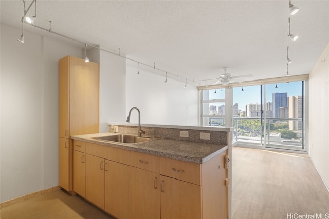 kitchen with track lighting, a textured ceiling, ceiling fan, sink, and light brown cabinets