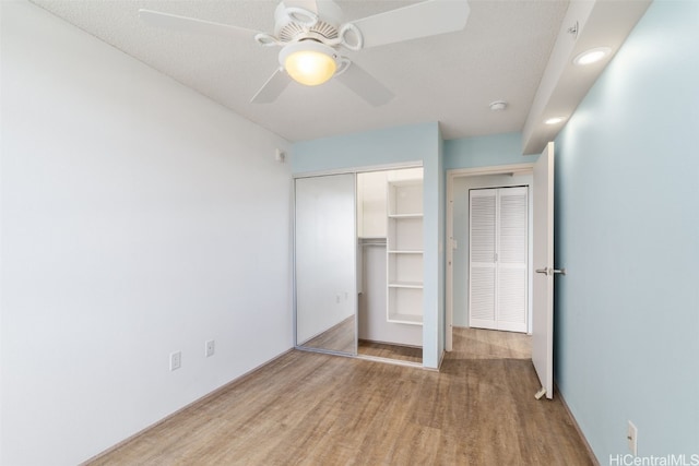 unfurnished bedroom featuring a closet, ceiling fan, light hardwood / wood-style flooring, and a textured ceiling