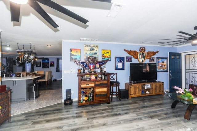 living room featuring hardwood / wood-style flooring, ceiling fan, and crown molding