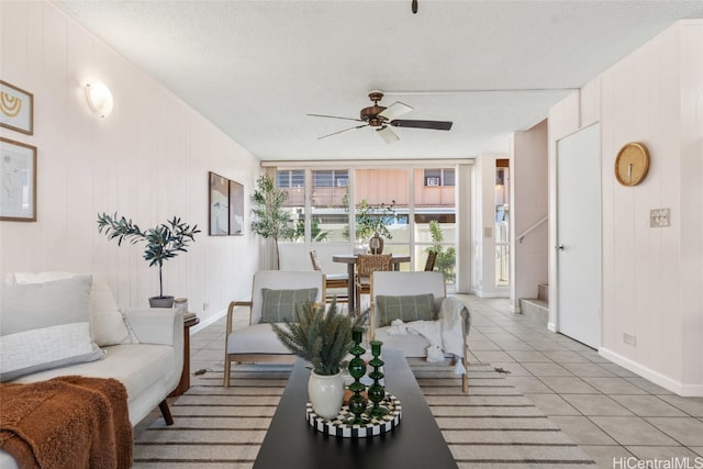 living room with ceiling fan, light tile patterned floors, and a textured ceiling