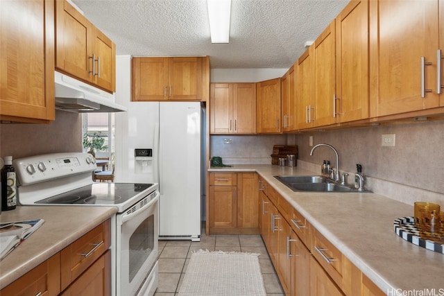 kitchen featuring light tile patterned floors, white appliances, a textured ceiling, and sink