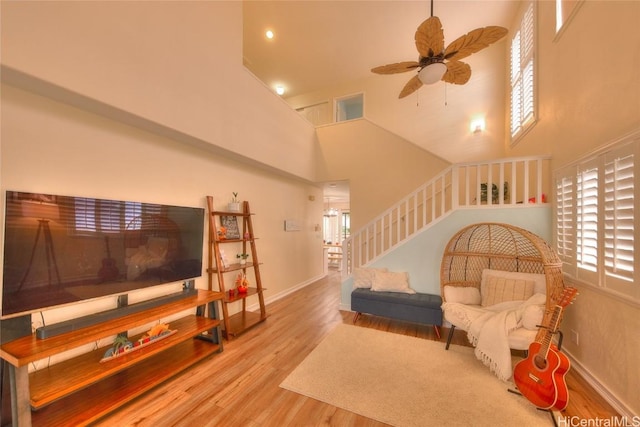 living room with a high ceiling, light wood-type flooring, and ceiling fan