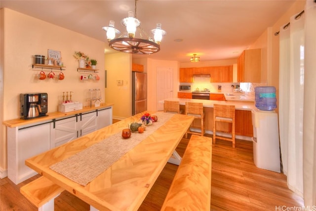 dining area with light wood-type flooring, sink, and an inviting chandelier