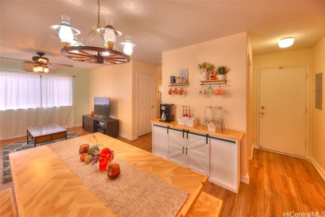 dining space featuring ceiling fan with notable chandelier and light hardwood / wood-style flooring