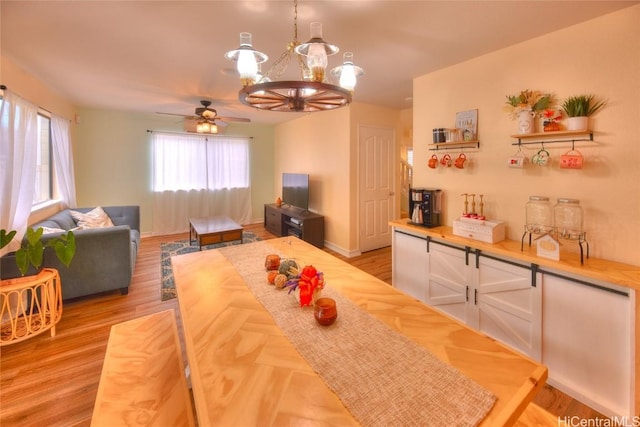 dining room featuring ceiling fan with notable chandelier and light hardwood / wood-style floors