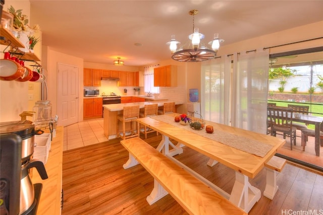 dining area featuring a chandelier, sink, and light hardwood / wood-style flooring