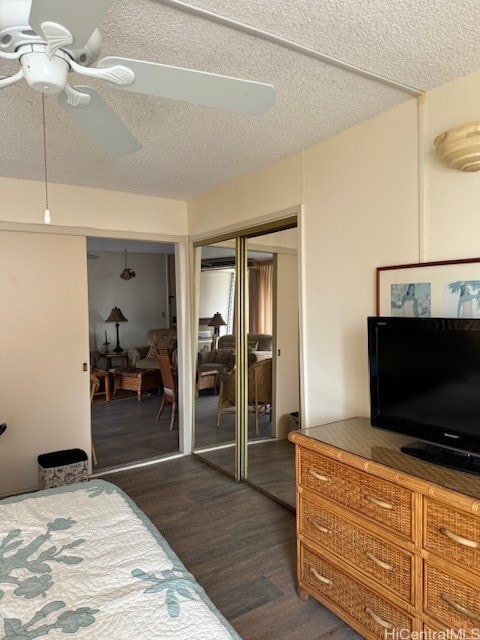 bedroom with ceiling fan, dark hardwood / wood-style flooring, a textured ceiling, and a closet