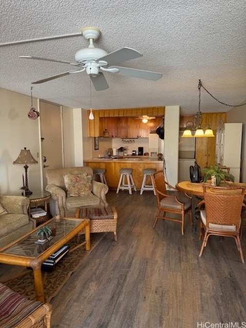 living room with ceiling fan with notable chandelier, dark hardwood / wood-style flooring, and a textured ceiling