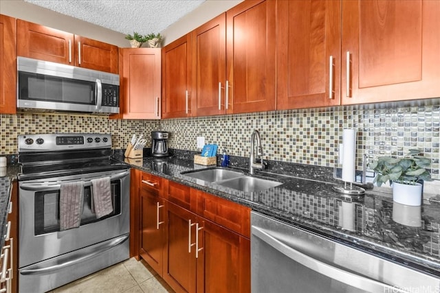 kitchen with decorative backsplash, appliances with stainless steel finishes, a textured ceiling, sink, and dark stone countertops