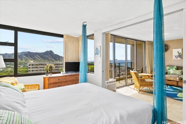 bedroom with a wall mounted air conditioner, expansive windows, a textured ceiling, access to outside, and light tile patterned floors