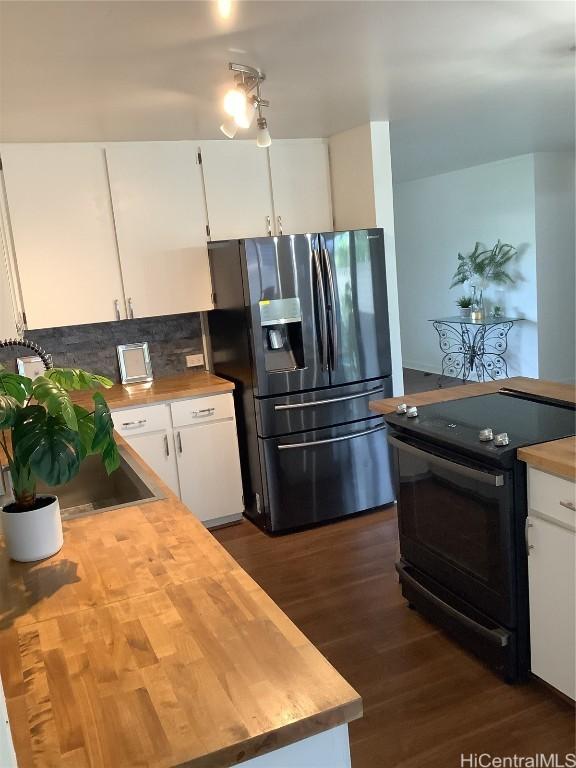 kitchen with black electric range oven, backsplash, stainless steel refrigerator with ice dispenser, dark hardwood / wood-style floors, and white cabinetry