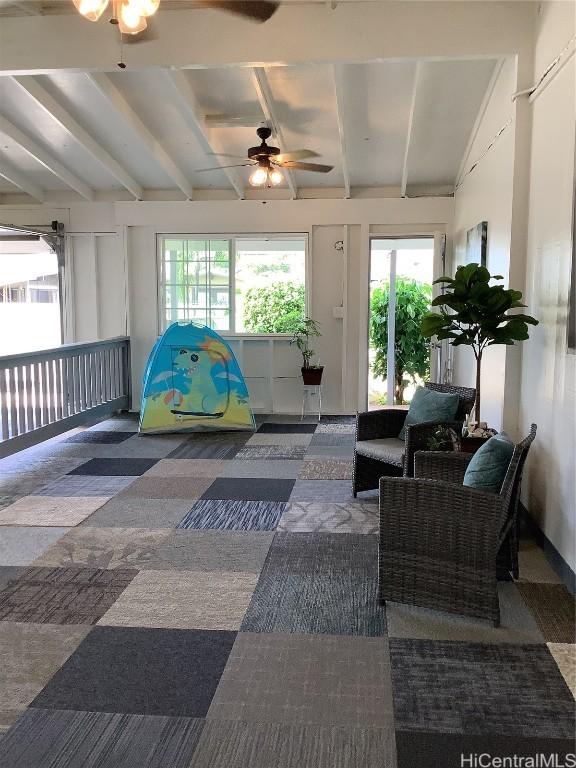 sunroom / solarium featuring ceiling fan and beam ceiling