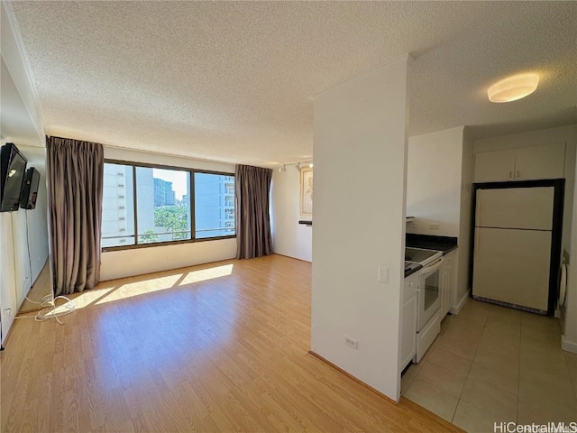 kitchen featuring a textured ceiling, white cabinets, light hardwood / wood-style floors, and white appliances