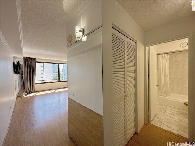 corridor with crown molding, wood-type flooring, and a textured ceiling